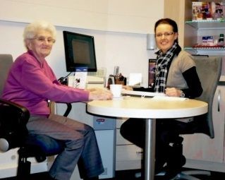 Eine Seniorin im Beratungsgespräch mit einer Mitarbeiterin in einem modernen Büro.